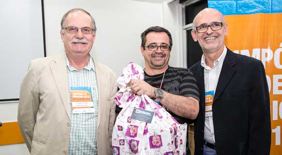 José Paulo Pereira, do Cond. Simas, com seu brinde, ao lado de Alberto Machado e do palestrante Sergio Simões